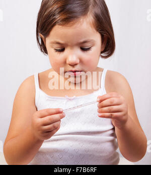 Little girl looking to a clinical mercury-in-glass thermometer Stock Photo