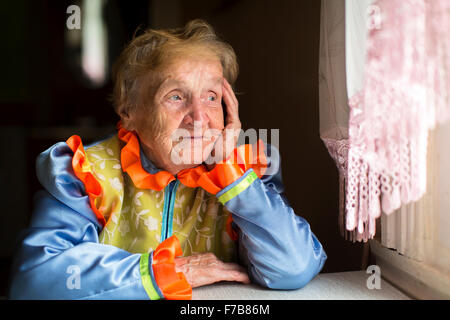 Elderly woman sadly looking out the window. Stock Photo