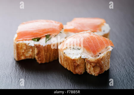 baguette slices with soft cheese and salmon on slate board Stock Photo
