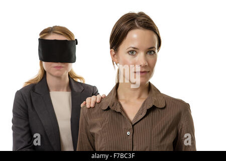 two business woman one blindfolded and the other helping Stock Photo