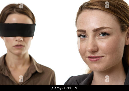 two business woman one blindfolded and the other helping Stock Photo