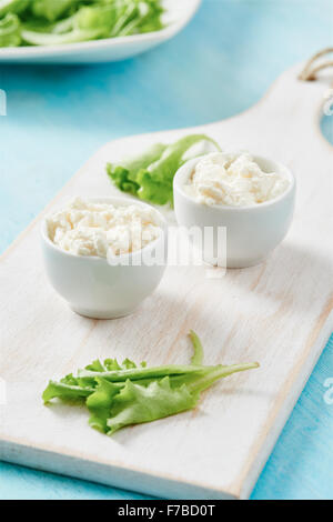 Cottage cheese in two white bowls on blue wooden table Stock Photo