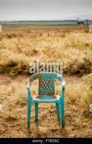 Grungy retro damaged plastic green chair abandoned in a field Stock Photo