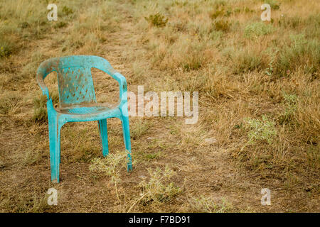 Grungy retro damaged plastic green chair abandoned in a field Stock Photo