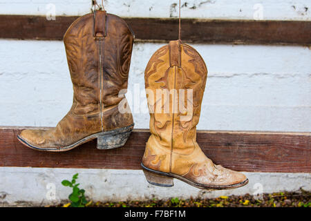 The old cowboy boots hanging on the bar in front of the stables Stock Photo