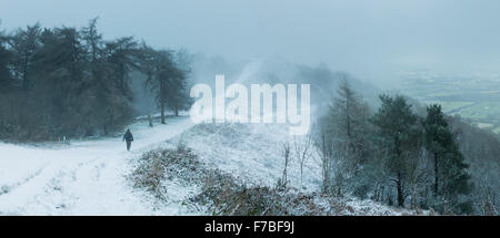 A walker walks along the snow covered footpath along the Malvern Hills from Pinnacle Hill to Jubilee Hill, Worcestershire. Stock Photo