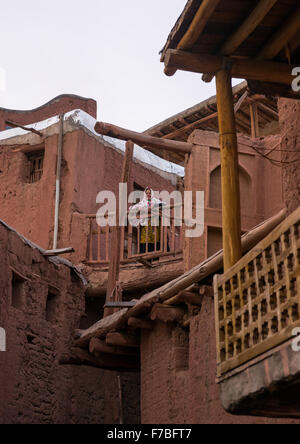 Iranian Woman Standing At The Balcony Of An Ancient Building In Zoroastrian Village, Isfahan Province, Abyaneh, Iran Stock Photo