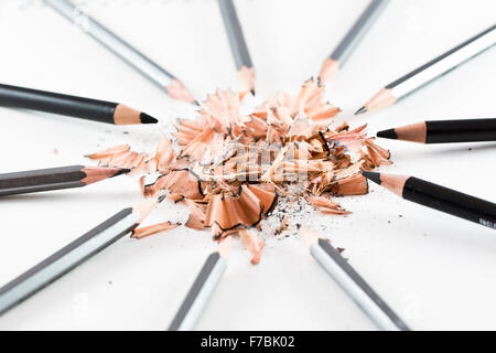 A pile of wooden shavings from a pencil surrounded by black & grey pencils Stock Photo
