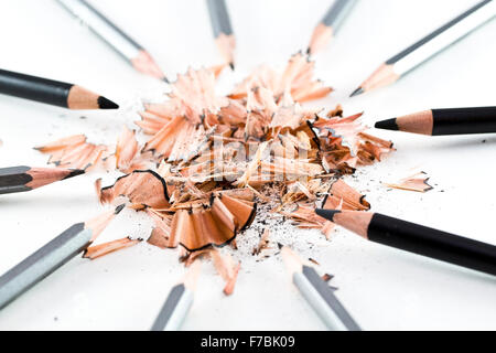 A pile of wooden shavings from a pencil surrounded by black & grey pencils Stock Photo