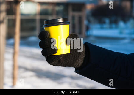 Moscow, Russia. Saturday, Nov. 28, 2015. Cold, but quiet and sunny weekend in Moscow, Russia. The temperature -2 degrees C (28,4 degrees F), no wind and plenty of sun after the many days of gloomy weather. Many people stay at home but some prefer to go for a walk of to do some skating in the Gorky Park. A hand of unidentified unrecognizable person holding a yellow plastic cup. Hot tea outdoors. The tea distributed by Raiffeisenbank. Credit:  Alex's Pictures/Alamy Live News Stock Photo