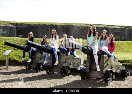 Eight happy teenage girls enjoying a fun day out sitting on the canons inside Broughty Ferry Castle Grounds in Dundee, UK