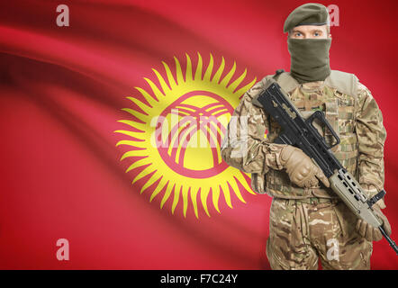 Soldier holding machine gun with national flag on background - Kyrgyzstan Stock Photo