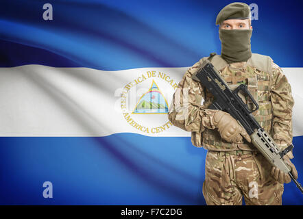 Soldier holding machine gun with national flag on background - Nicaragua Stock Photo