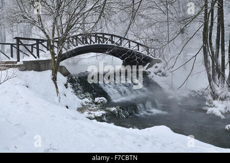 small wooden bridge over cold river at early mornig at winter season Stock Photo