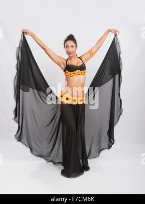 Young girl mulatto dancing in a long black candid open dress, is isolated on a light background Stock Photo