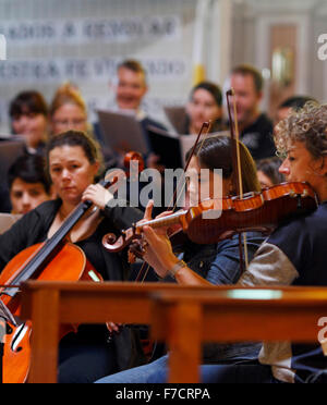 Two young women playing violin in a rehearsal, and a cellist alongside. Stock Photo