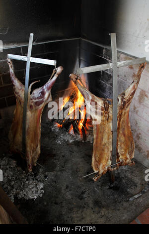 Asado barbecue. Lamb being roasted on a metal crucifix over and open charcoal fire Stock Photo