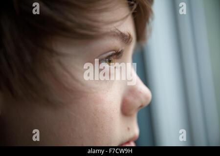 Close up of twelve year old boy looking out of window. Stock Photo