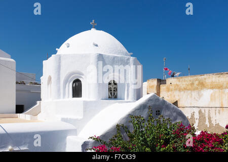 traditional Greek architecture of an dome of an orthodox church with some green vegetation and colorful clothes hanging outside Stock Photo