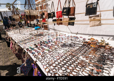 Handbags, jewelry and leather goods including fake for sale at a stall in the Sunday Market in the Lanzarote town of Teguise Stock Photo