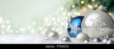 Panoramic Christmas background with nice shiny baubles on snow and defocused lights in the background, with light green copy spa Stock Photo