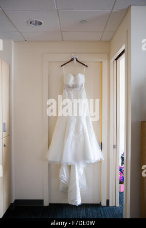 White wedding dress hanging on a door frame at a hotel before a ceremony. Stock Photo