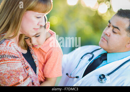 Sick Mixed Race Boy, His Mother and Hispanic Doctor Outdoors. Stock Photo