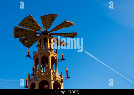 Christmas Pyramid or carousel, Cathedral Gardens, Manchester, England, UK.  Aircraft contrail in the sky above. Stock Photo