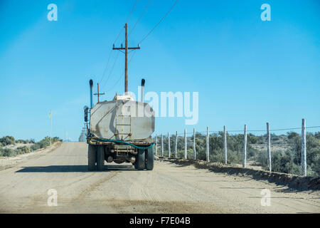 watering truck sprays to keep down dust on road leading to new beach development politely stops as car approaches Puerto Penasco Stock Photo