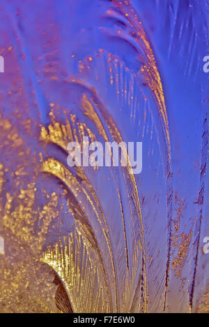 Icy frosty ornate pattern of thin ice on the window in the background of the dawn. Stock Photo