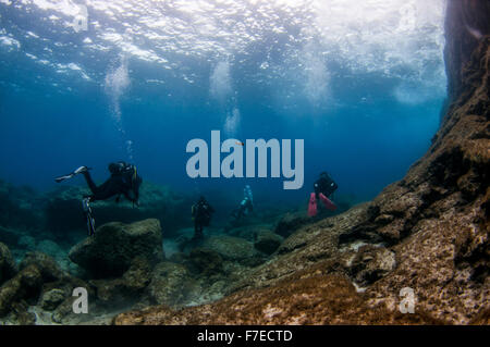 Divers explore natural caves and rocks in the Mediterranean sea off the coast of Larnaca, Cyprus, Stock Photo