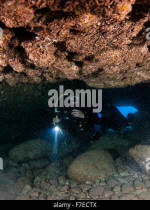 Divers explore natural caves and rocks in the Mediterranean sea off the coast of Larnaca, Cyprus, Stock Photo