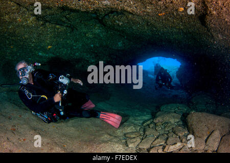 Divers explore natural caves and rocks in the Mediterranean sea off the coast of Larnaca, Cyprus, Stock Photo