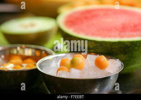 Fruit salad, scooping balls of sweet melon into a bowl of ice. This image has a restriction for licensing in Israel Stock Photo
