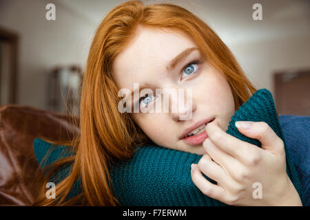 Thoughtful attractive redhead young lady hugging knitted pillow Stock Photo