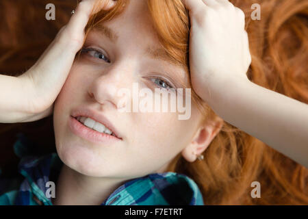 Closeup of lovely cute redhead girl in blue checkered shirt lying on the floor with tousled hair Stock Photo