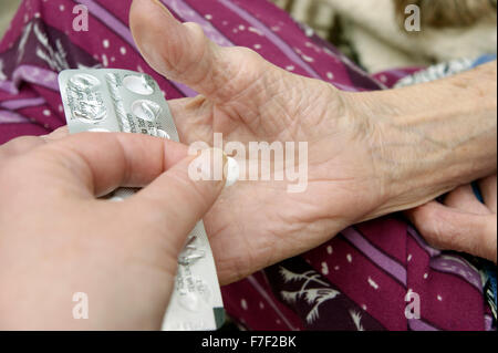 Female carer / daughter giving a tablet to a disabled elderly woman (mother) Stock Photo