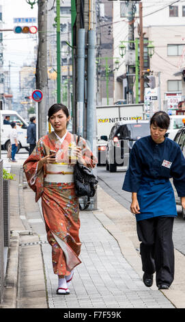 Lady walking round streets of Kyoto in  Japan wearing traditional Japanese Kimono and traditional footwear Zori or geta Stock Photo