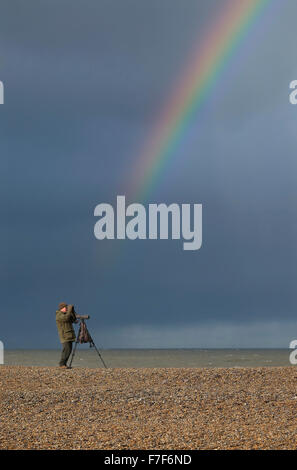 bird watcher and rainbow on cley beach, norfolk, england Stock Photo