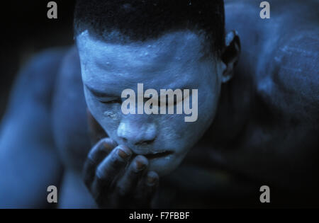 Young Xhosa initiate, who is going through the traditional Xhosa male initiation rite, is painting his face with white clay Stock Photo