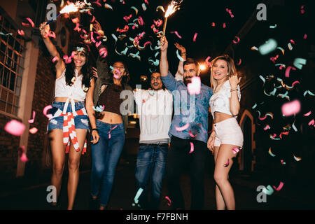 Group of young people having a party, outdoors. Multiracial young men and women celebrating with confetti. Best friend having pa