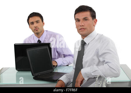 Two businessmen sat at the same desk Stock Photo