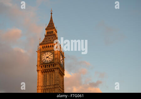 The top of the Big Ben clock tower in the late afternoon sunlight of sunset with a blue sky and some clouds in London, UK. Stock Photo