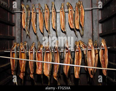 Prepared whole smoked herrings (kippers) hang in a wooden smoking cabinet  on sale at a farmers market,  England UK Stock Photo