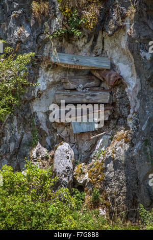 Old wooden coffins hang from cliff faces in the karst limestone rock formations of the Grand Cordillera Mountain range in Sagada Stock Photo