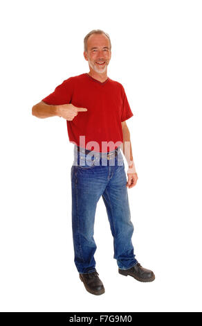 A smiling middle age man in jeans and red t-shirt standing isolated for white background and pointing at himself. Stock Photo