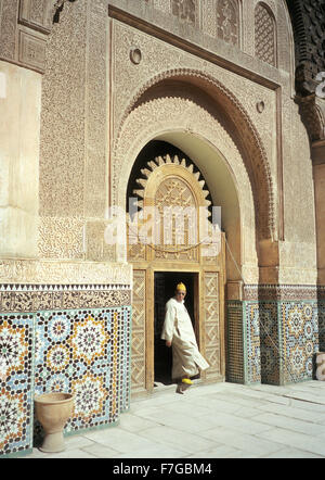 A Muslim Moroccan man steps into the courtyard at Ali ben Youssef Medersa inside the medina at Marrakech, Morocco, North Africa. Stock Photo