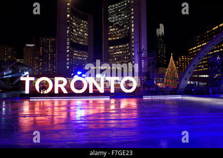 Ice rink at Nathan Phillips Square at night with City Hall and Toronto sign Stock Photo
