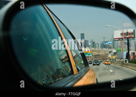 NEW YORK - JUNE 28: New York yellow cabs in motion by a city street scene with the skyline at bottom, reflected in rear mirror. Stock Photo