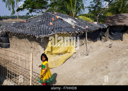 COX's BAZAR, BANGLADESH - November 28: A girl standing beside her house which is affected by sea level rising in Kutubdia Island in Cox's Bazar District in Dhaka on November 28, 2015.  Kutubdia, an island off the Cox's Bazar coast. the adversities of nature induced mainly by climate change. During the last two decades the impacts of climate in Bangladesh have been accellerating.Kutubdia is also hit hard. The place is very vulnerable to cyclones and storm surges, which have become more frequent and intense in Bangladesh, as well as rising sea-level and stronger waves. The result is massive eros Stock Photo